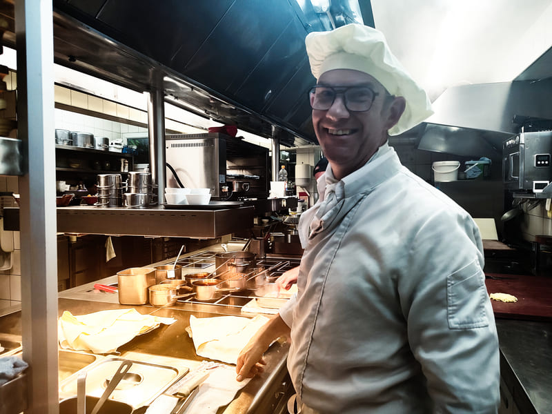 Portrait de François Morand, chef de cuisine et propriétaire du restaurant La Diligence à Saint-Louis. Le chef est photographié dans sa cuisine, illustrant le savoir-faire alsacien.