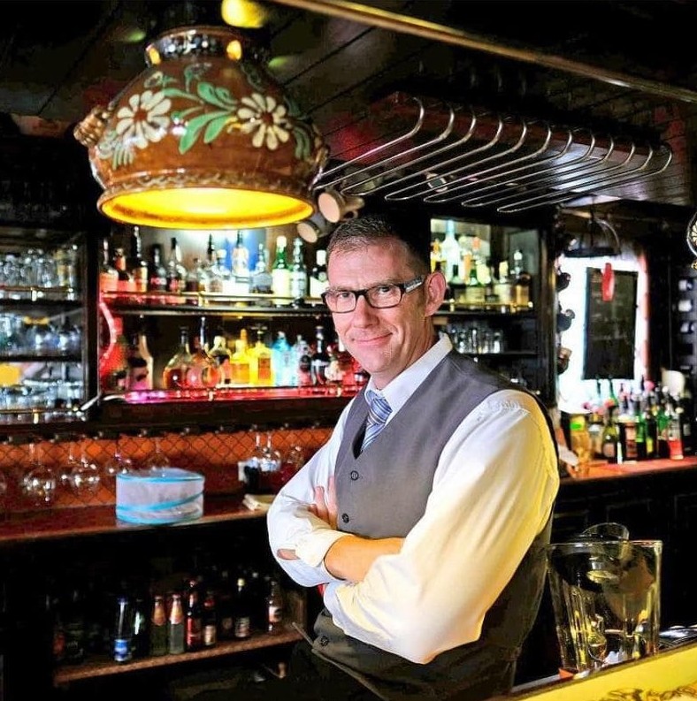 François Morand, le propriétaire, souriant et accueillant au bar du restaurant La Diligence.